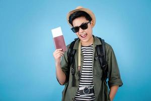 los turistas asiáticos disfrutan de sus vacaciones mientras sostienen un pasaporte en un fondo azul en el estudio. foto