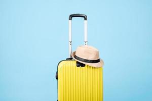 A yellow suitcase with a hat on a blue background photo