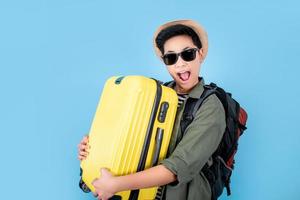 los turistas son felices y sonrientes con una maleta amarilla en la bolsa de fondo azul. foto