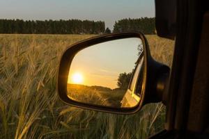 reflejo en el espejo del atardecer en el campo de trigo foto