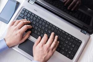 man behind laptop with smartphone photo