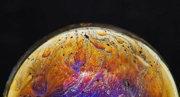 Virtual reality space with abstract multicolor psychedelic planet. Closeup Soap bubble like an alien planet on black background photo