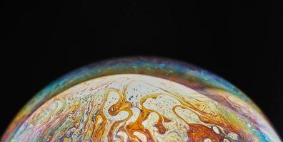 Virtual reality space with abstract multicolor psychedelic planet. Closeup Soap bubble like an alien planet on black background photo