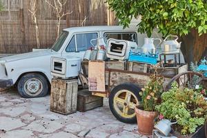 Old car, wheelbarrow with antique utensils made of wood and metal, to decorate the courtyard of the cafe photo