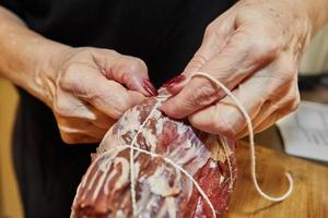 el chef ata la carne con una cuerda y la prepara para hornearla en el horno foto