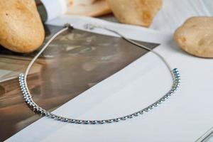 Silver chain with blue stones on gray-white background photo