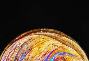 Virtual reality space with abstract multicolor psychedelic planet. Closeup Soap bubble like an alien planet on black background photo