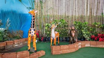 The broad giraffes and the monkeys stand lined up in a row. Behind it is a tree and a wooden wall photo