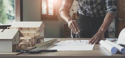 Concept architects, engineer holding pen pointing equipment architects On the desk with a blueprint in the office, Vintage, Sunset light.Selective Focus photo