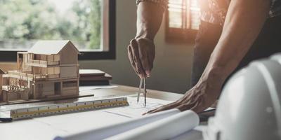 Concept architects, engineer holding pen pointing equipment architects On the desk with a blueprint in the office, Vintage, Sunset light.Selective Focus photo