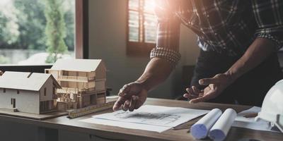 Concept architects, engineer holding pen pointing equipment architects On the desk with a blueprint in the office, Vintage, Sunset light.Selective Focus photo