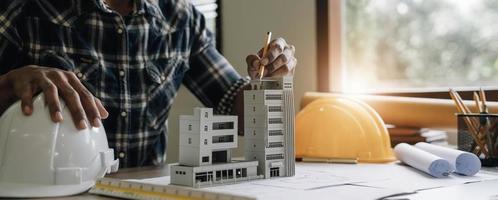 Image of engineer drawing a blue print design building or house, An engineer workplace with blueprints, pencil, protractor and safety helmet, Industry concept photo