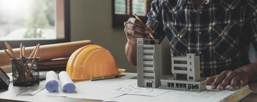 Image of engineer drawing a blue print design building or house, An engineer workplace with blueprints, pencil, protractor and safety helmet, Industry concept photo