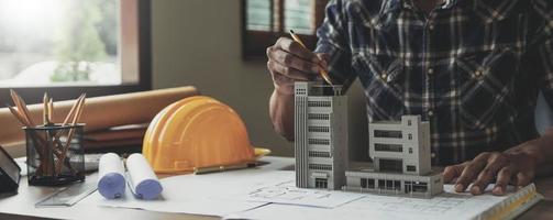 imagen de ingeniero dibujando un edificio o casa de diseño de impresión azul, un lugar de trabajo de ingeniero con planos, lápiz, transportador y casco de seguridad, concepto industrial foto