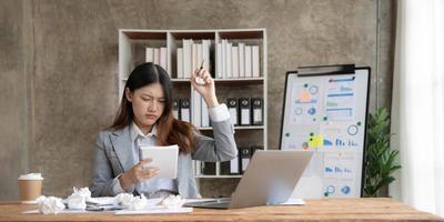 asian woman thinking hard concerned about online problem solution looking at laptop screen, worried serious asian businesswoman focused on solving difficult work computer task photo