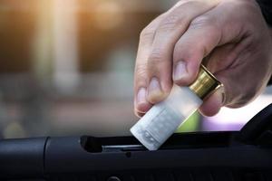 Shotgun man is inserting new shotshell bullets on shotgun, soft and selective focus. photo