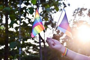 bandera del arco iris y pulseras en las manos, enfoque suave y selectivo, concepto para celebraciones de géneros lgbtq y llamando a todas las personas a respetar los derechos humanos en el mes del orgullo en todo el mundo. foto