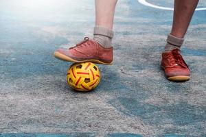 joven jugador de sepak takraw masculino del sudeste asiático usando su tobillo derecho para sostener la pelota en el área central de servicio de la cancha, sepak takraw al aire libre jugando después de la escuela, enfoque suave y selectivo. foto