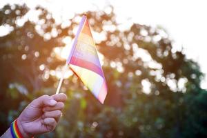 bandera del arco iris y pulseras en las manos, enfoque suave y selectivo, concepto para celebraciones de géneros lgbtq y llamando a todas las personas a respetar los derechos humanos en el mes del orgullo en todo el mundo. foto