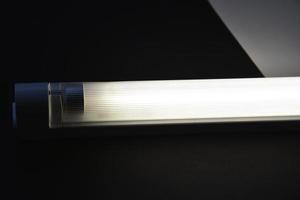 LED lamp on the desk. Glowing fluorescent lamp and LED on a black table. photo
