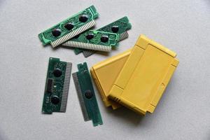 Electronic cartridge board for retro game console. A yellow plastic cartridge on a black background and an electronic board. photo