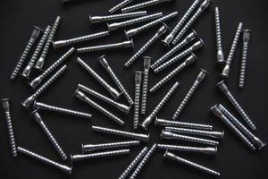 Shiny steel bolts for fixing furniture. Accessories on a black background. photo