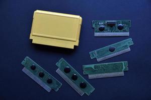 Electronic cartridge board for retro game console. A yellow plastic cartridge on a black background and an electronic board. photo