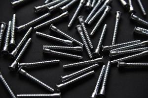 Shiny steel bolts for fixing furniture. Accessories on a black background. photo