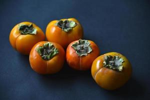 Orange persimmon fruits on a black background. Ripe and juicy persimmon fruits close-up. photo