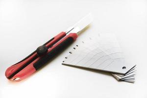 Red stationery knife with blades on a white background. Cutting tool with blades on a white background. photo