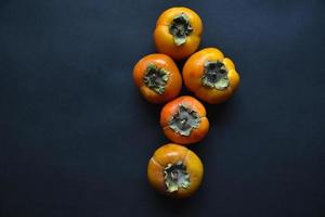 Orange persimmon fruits on a black background. Ripe and juicy persimmon fruits close-up. photo
