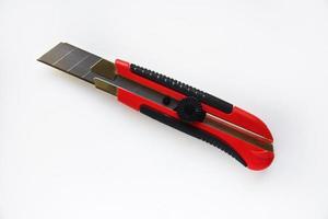 Red stationery knife with blades on a white background. Cutting tool with blades on a white background. photo