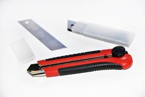 Red stationery knife with blades on a white background. Cutting tool with blades on a white background. photo