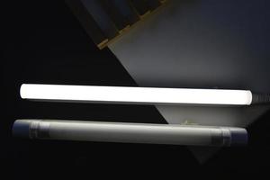 LED lamp on the desk. Glowing fluorescent lamp and LED on a black table. photo