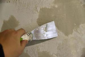 trabaje con una espátula de hierro al enlucir la pared con una solución de cemento. reparación de la pared con una paleta con cemento. foto