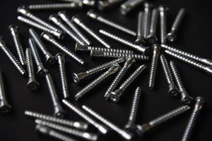 Shiny steel bolts for fixing furniture. Accessories on a black background. photo