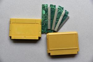 placa de cartucho electrónico para consola de juegos retro. un cartucho de plástico amarillo sobre un fondo negro y una placa electrónica. foto