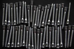 Shiny steel bolts for fixing furniture. Accessories on a black background. photo