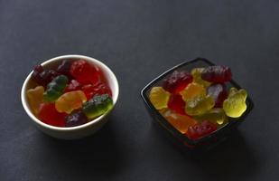 osos de mermelada de gelatina en una taza de cerámica sobre un fondo negro. primer plano de dulces coloridos de mermelada. foto