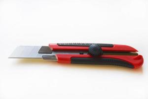 Red stationery knife with blades on a white background. Cutting tool with blades on a white background. photo