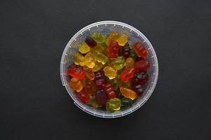 Jelly marmalade bears in a ceramic cup on a black background. Marmalade colorful candies close-up. photo