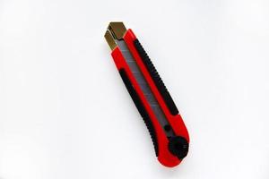 cuchillo de papelería rojo con cuchillas sobre un fondo blanco. herramienta de corte con cuchillas sobre un fondo blanco. foto