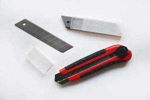 Red stationery knife with blades on a white background. Cutting tool with blades on a white background. photo