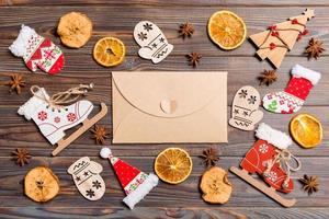vista superior del sobre sobre fondo de madera festiva. juguetes y adornos navideños. concepto de tiempo de año nuevo foto