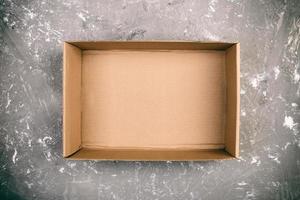 Opened brown blank cardboard box on cement gray background vintage, toned, top view photo