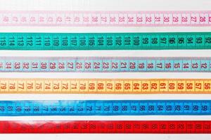 Close up of a group of colorful measure tapes lying in rows as a background. Diet concept on wooden background photo