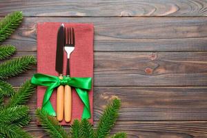 Top view of christmas decorations on wooden background. Fork and knife on napkin tied up with ribbon and empty space for your design. New year pattern concept photo