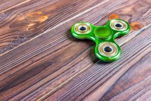 Green fidget spinner stress relieving toy on wood background photo