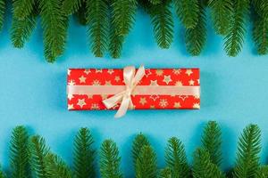 Top view of fir tree branches and gift box on colorful background. Christmas time concept with empty space for your design photo