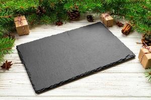 Perspective view. Empty black slate rectangular plate on wooden christmas background. holiday dinner dish concept with new year decor photo